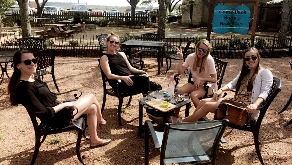 Four women sitting around a table with snacks and wine at Fiesta Winery's outdoor patio.