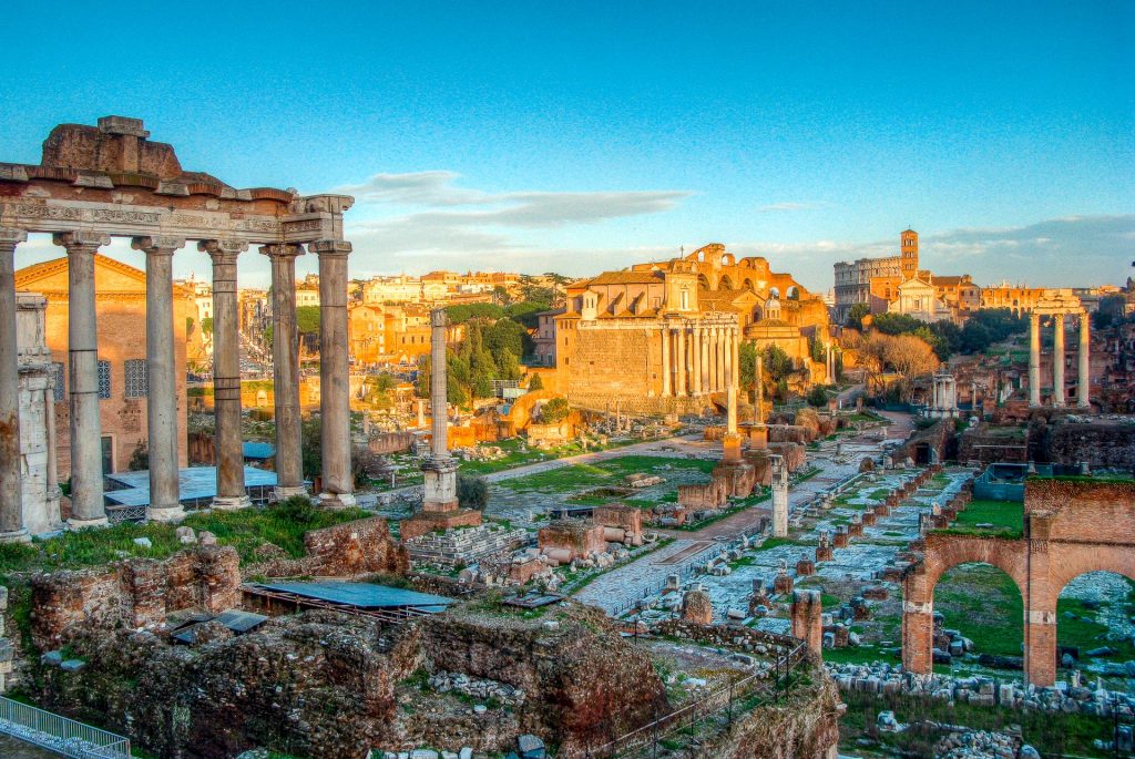 Gorgeous photo of the sunrise at the Roman Forum - ruins of giant columns standing tall and archways.