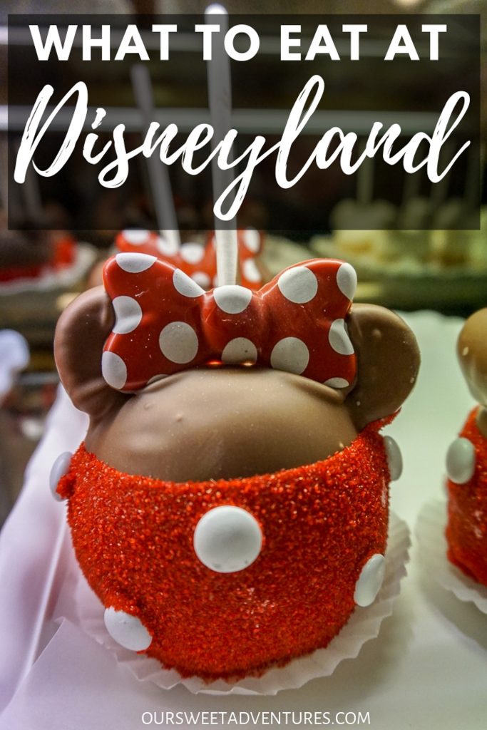 A chocolate caramel apple with red sugar sprinkles on the bottom with white M&Ms and a bow to resemble Minnie Mouse with text overlay "What to Eat at Disneyland"