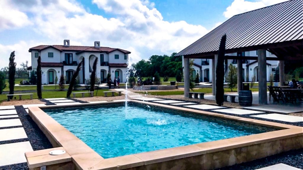 Beautiful rectangle pool with a little fountain and an European villa and covered patio from Barons Creek Vineyard in Fredericksburg, Texas.