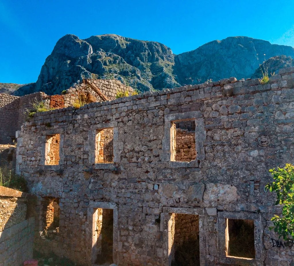 Kotor's castle ruins of a 6th century stone wall with small rectangle windows.
