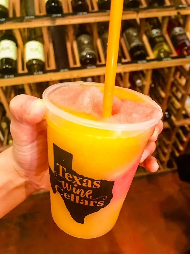 A plastic cup filled with an orange peach Bellini from Texas Wine Cellars. 