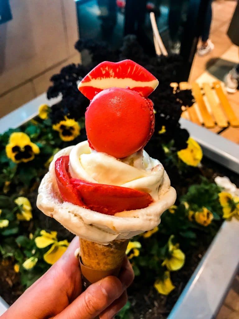 A gelato rose bouquet with a red macaron and a lipstick chocolate piece on top from Amorino.