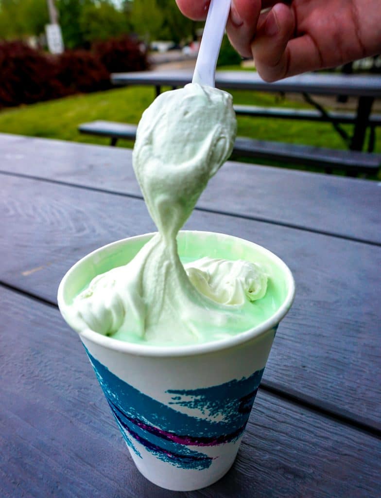 A cup full of Lyon's frozen custard with a spoon dipping into it. 