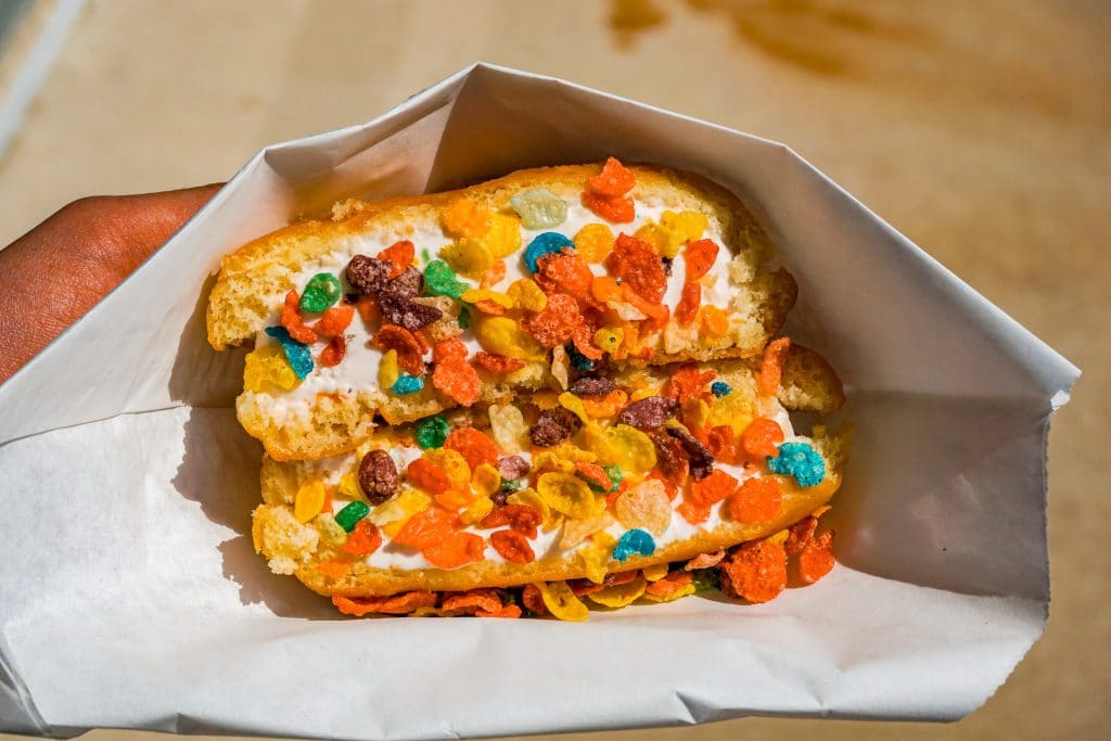 A donut filled with ice cream and covered in Fruity Pebbles from one of the best ice cream shops in Dallas - Milky Treats in Plano. 