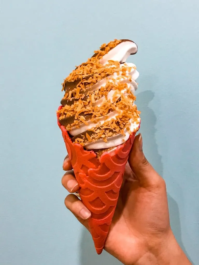 A swirl of chocolate and coconut soft serve ice cream inside a red waffle cone from Sugar Pine Creamery in Plano.