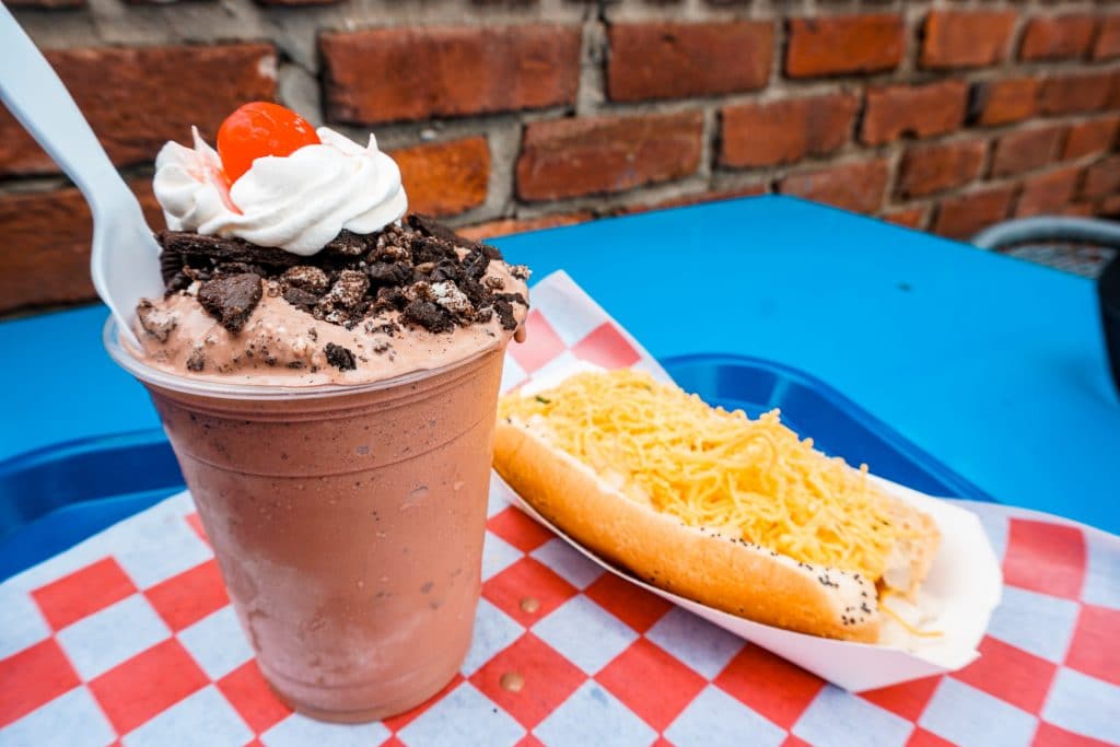 A chocolate custard with chocolate cookie crumbs, whipped cream and a cherry on the left and a hot dog covered in cheese on the right from Wild About Harrys - one of the best ice creams in Dallas.
