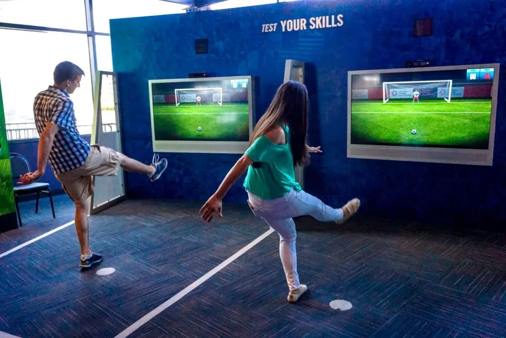 A couple playing with the interactive exhibit kicking a virtual soccer ball at the Soccer Hall of Fame. 