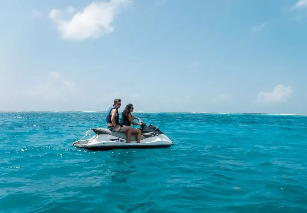 A couple riding on a jet ski in the deep blue ocean because it is one of the best things to do in the Grand Cayman.