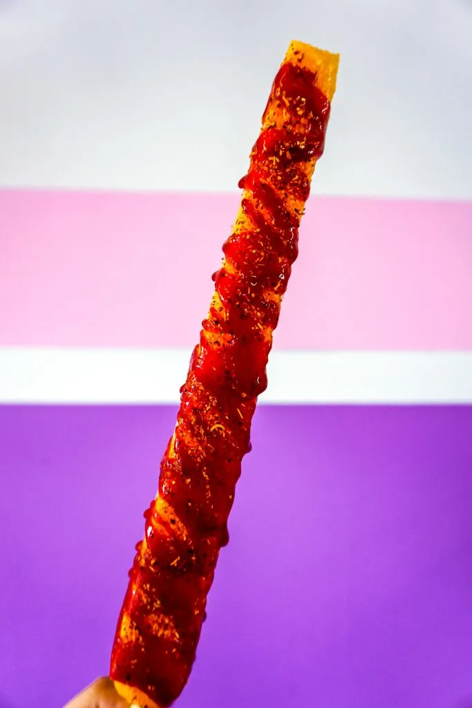 A foot-long spicy mango paleta drizzled with chamoy.