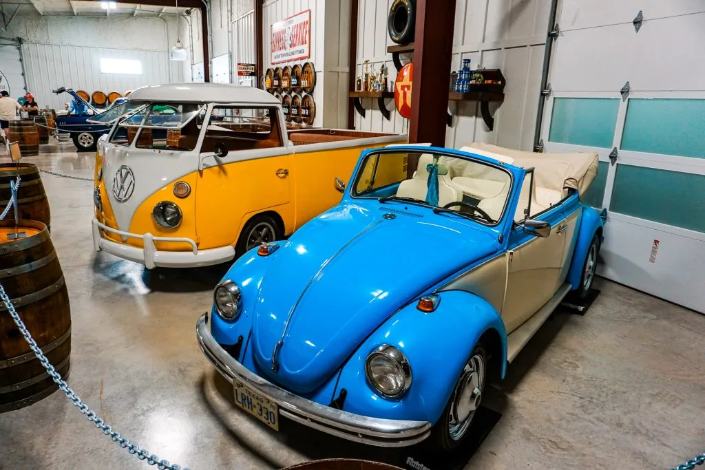 A light blue classic slug bug and a yellow Volkswagen bus behind it. 