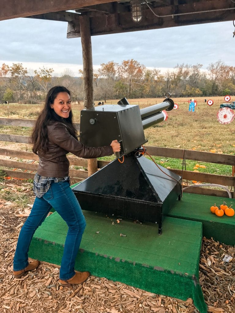 A woman posing while shooting from a pumpkin blaster at a farm near Washington D.C. in the fall.