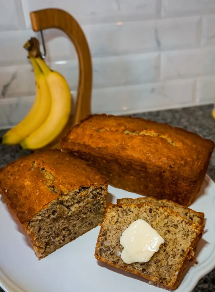 A trio of the best banana nut bread recipe - half a loaf, a full loaf, and two slices with a slab of butter on top. 