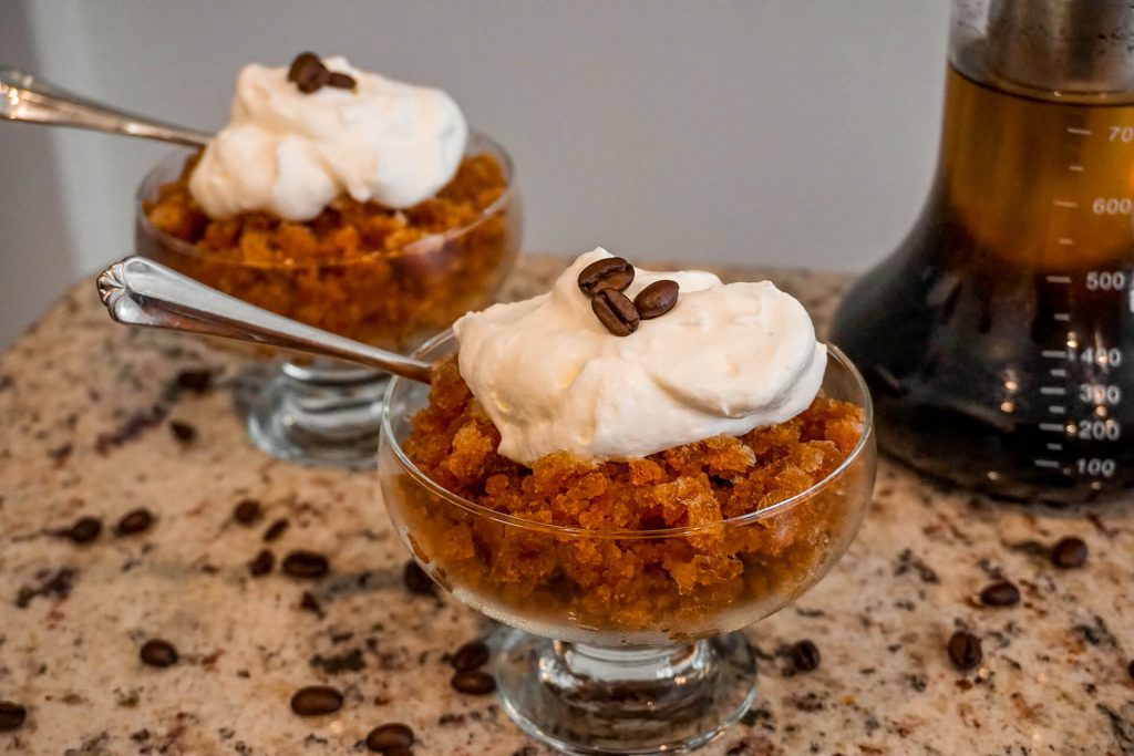 Two bowls filled with cold brew coffee granita and a dollop of whipped cream on top - the perfect frozen dessert.