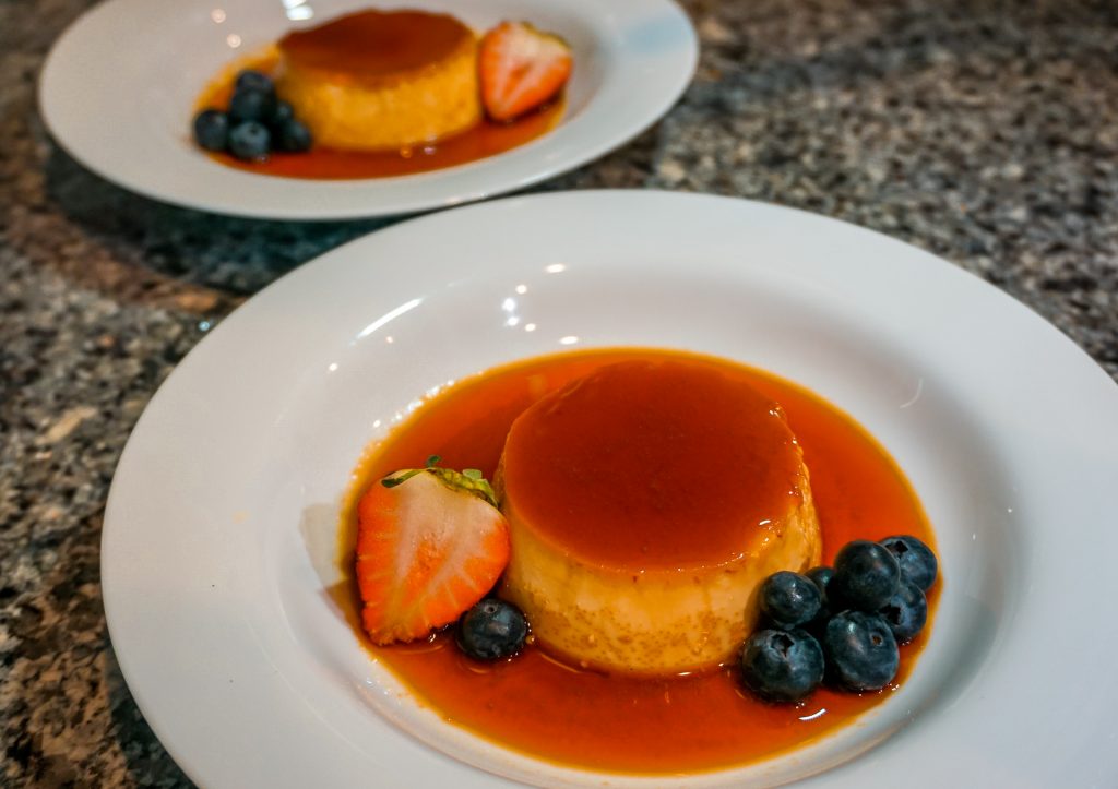 Two plates of Instant Pot flan (creme caramel) with mixed berries. 