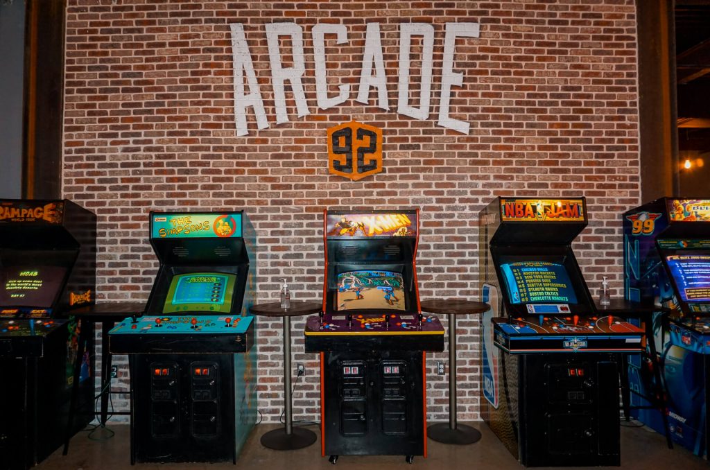 Classic arcade games lines up against a brick wall from Arcade 92 in McKinney, Texas.