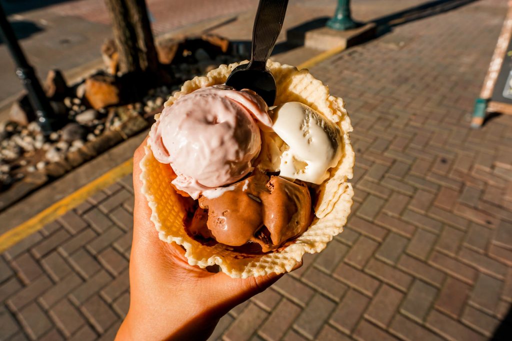 Someone holding a waffle bowl with three scoops of boozy ice cream from Cocktail Creamery.