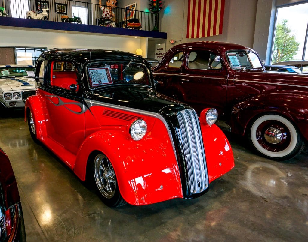 A classic red and black car in a showcase room. 
