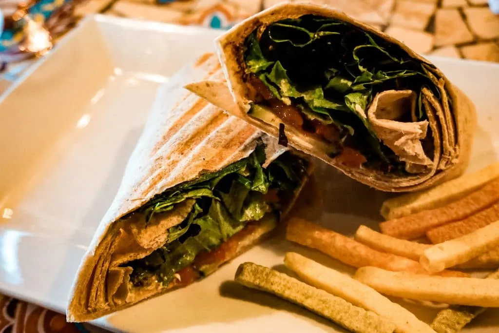 A veggie wrap with a side of veggie straws on a plate. 