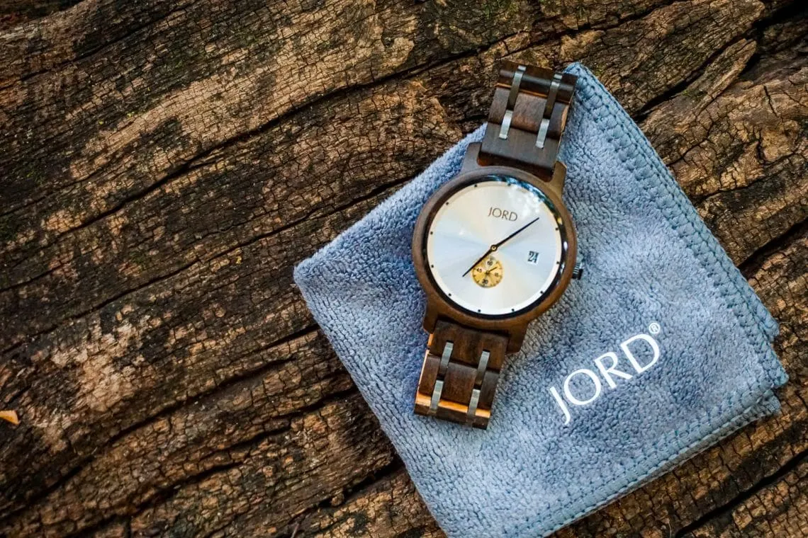 A JORD Hyde wooden watch on top of a gray square cloth resting on a wooden log.