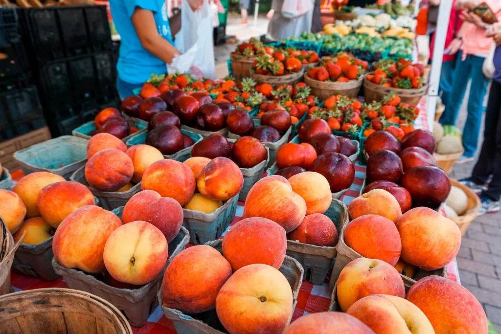 Fresh peaches, nectarines, and strawberries at a farmer's market.