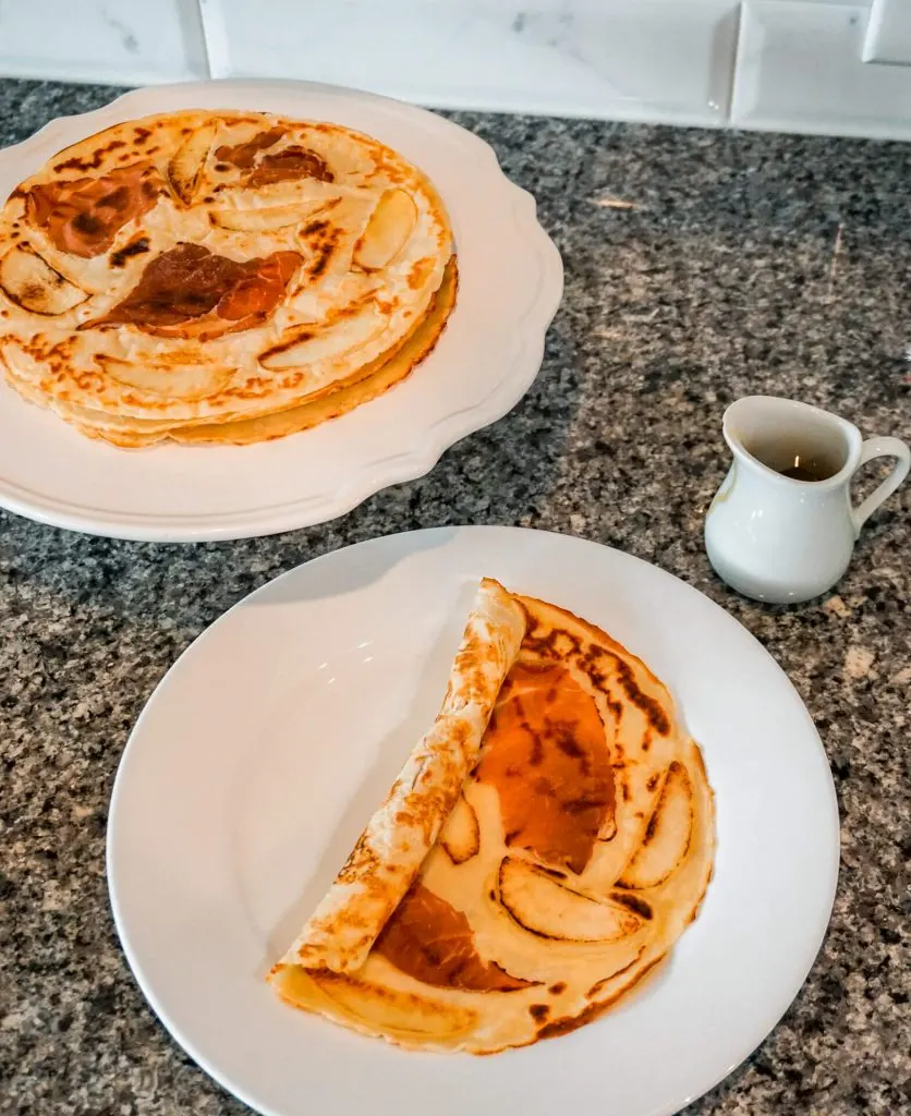 A stack full of Dutch pancakes (pannekoek) alongside a plate with the Dutch pancake folded over.