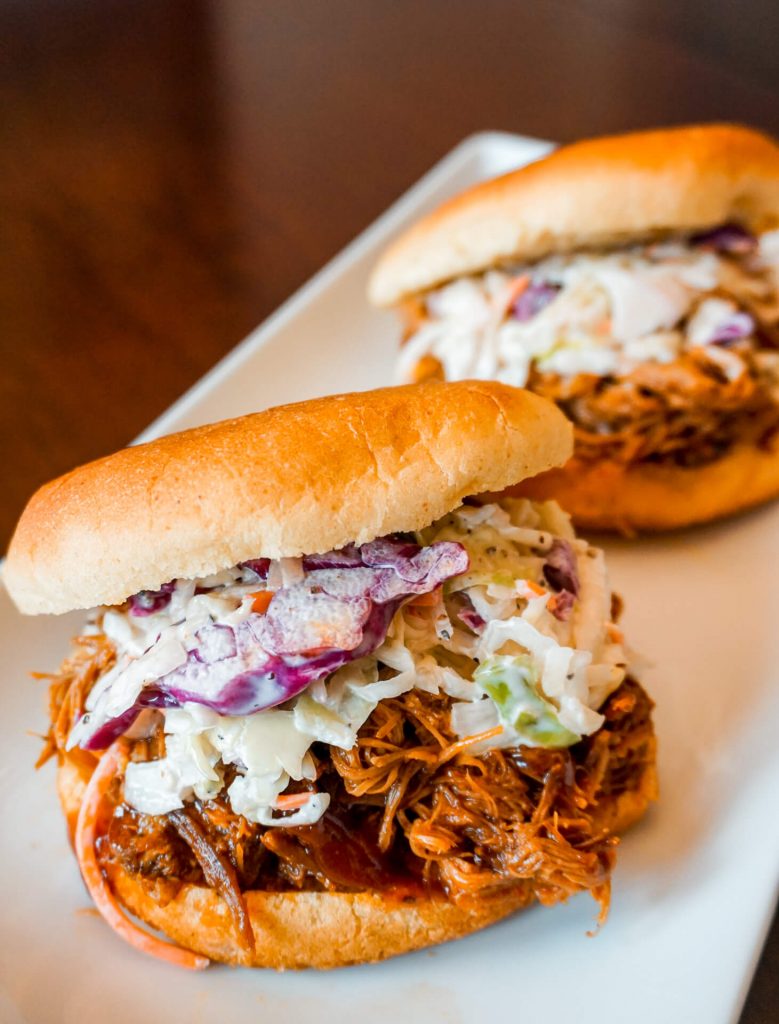 A hamburger bun with coleslaw and juicy, Texas pulled pork.
