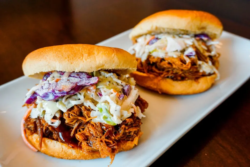 Two Texas pulled pork sandwiches on hamburger buns with coleslaw. 