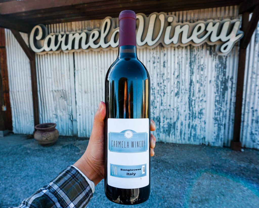 A bottle of Carmela Winery's popular Sangiovese in front of their winery.