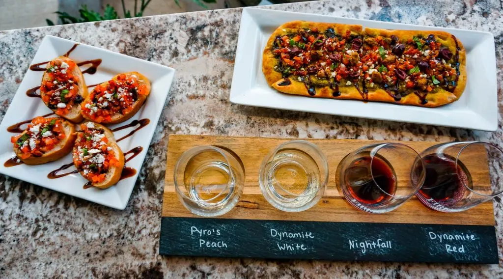 A birds-eye view of a wine flight, plate of bruschetta, and a plate of Sicilian flatbread from Firelight Vineyards - one of the best wineries in North Texas. 