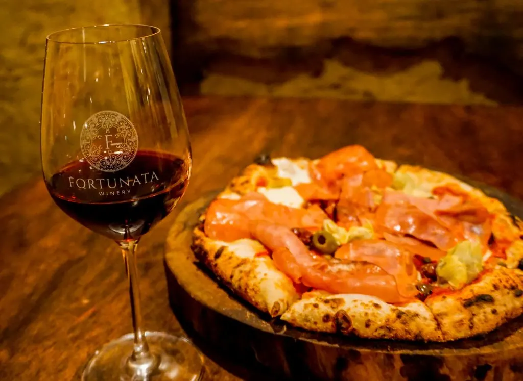 A glass of red wine and a wood-fired pizza from Fortunata Winery.