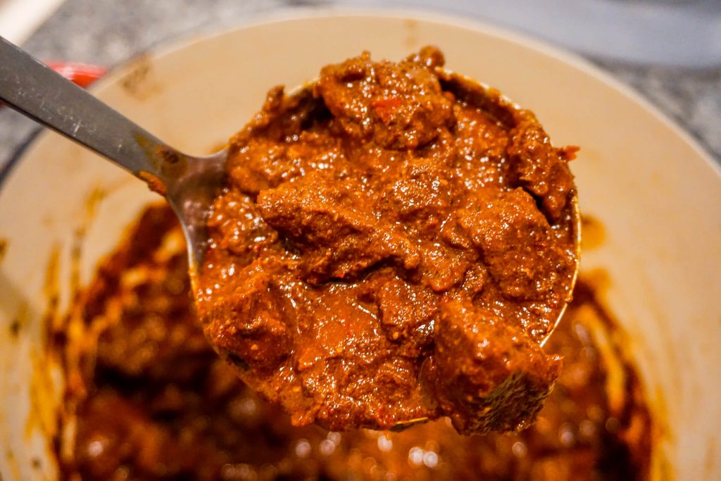A ladle of Texas Chili with homemade chili paste and chunks of beef chuck roast.