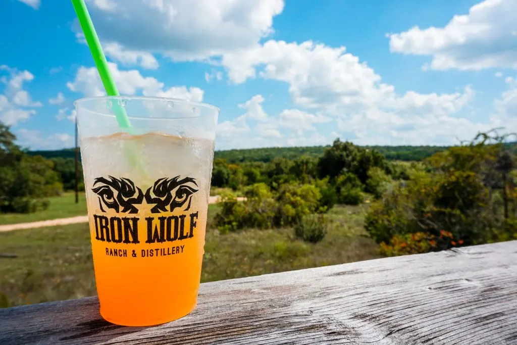 A mixed cocktail from Iron Wolf Ranch & Distillery with the Texas Hill Country in the backdrop.