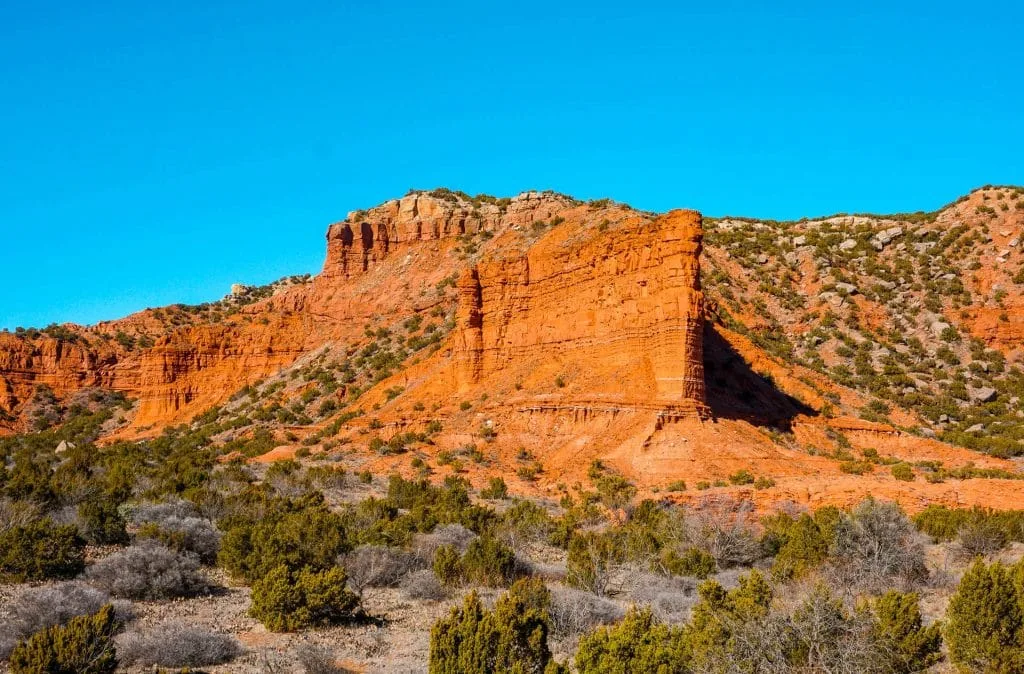 A beautiful overlook of a towering red rock formation with canyons behind it at at Upper South Prong - one of the best things to do in Caprock Canyons State Park. 