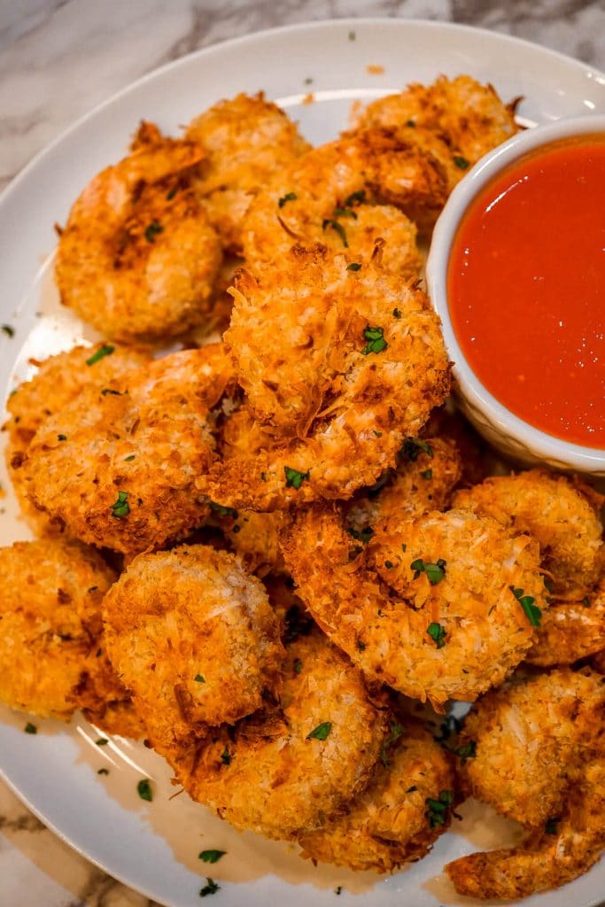 A plate of air fryer coconut shrimp with parsley sprinkled on top.