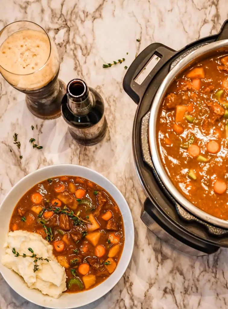 Birdseye view of a glass and bottle of Guinness alongside an Instant Pot and bowl full of Guinness Beef Stew.