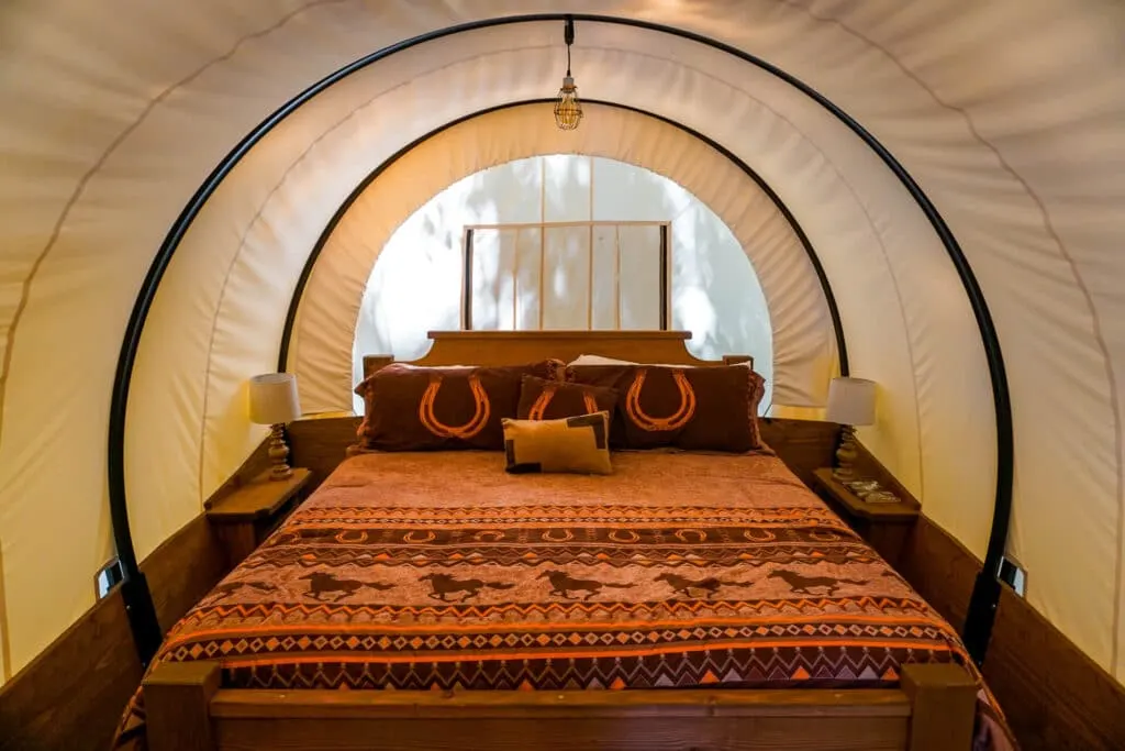 Inside a Conestoga Covered Wagon with a king-sized bed and an Old Western decorative blanket.