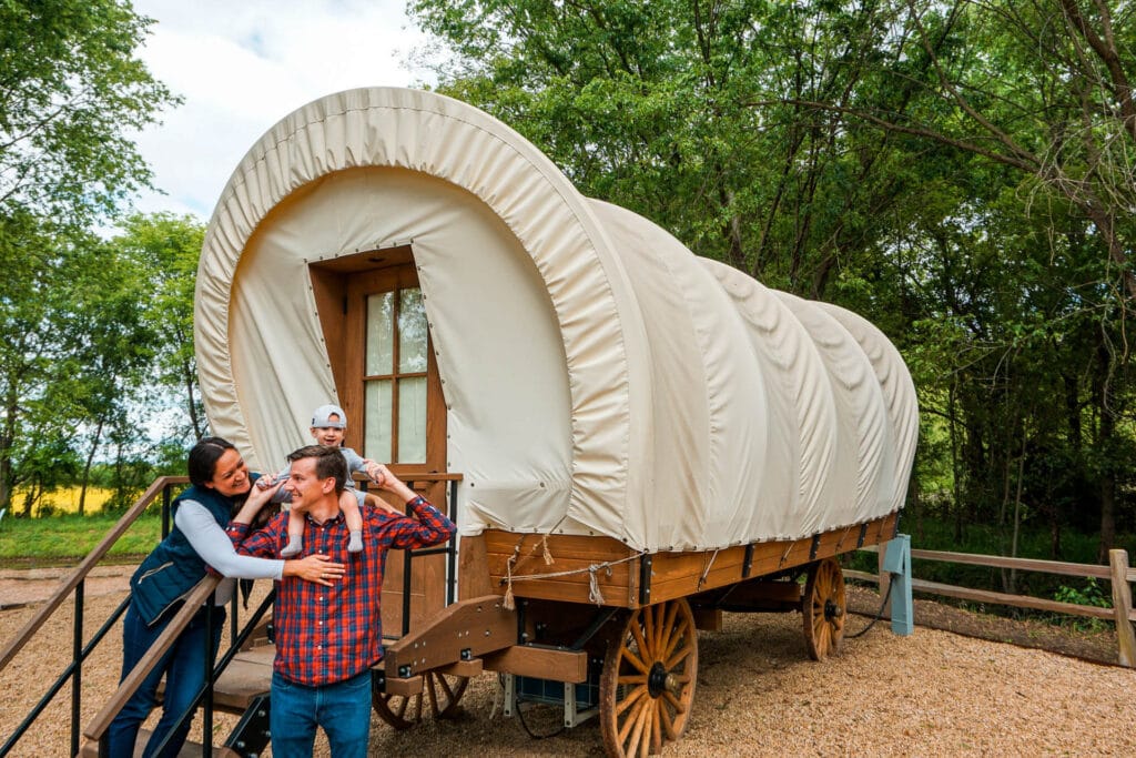 A family in front of a Conestoga Covered Wagon at The Silver Spur Resort