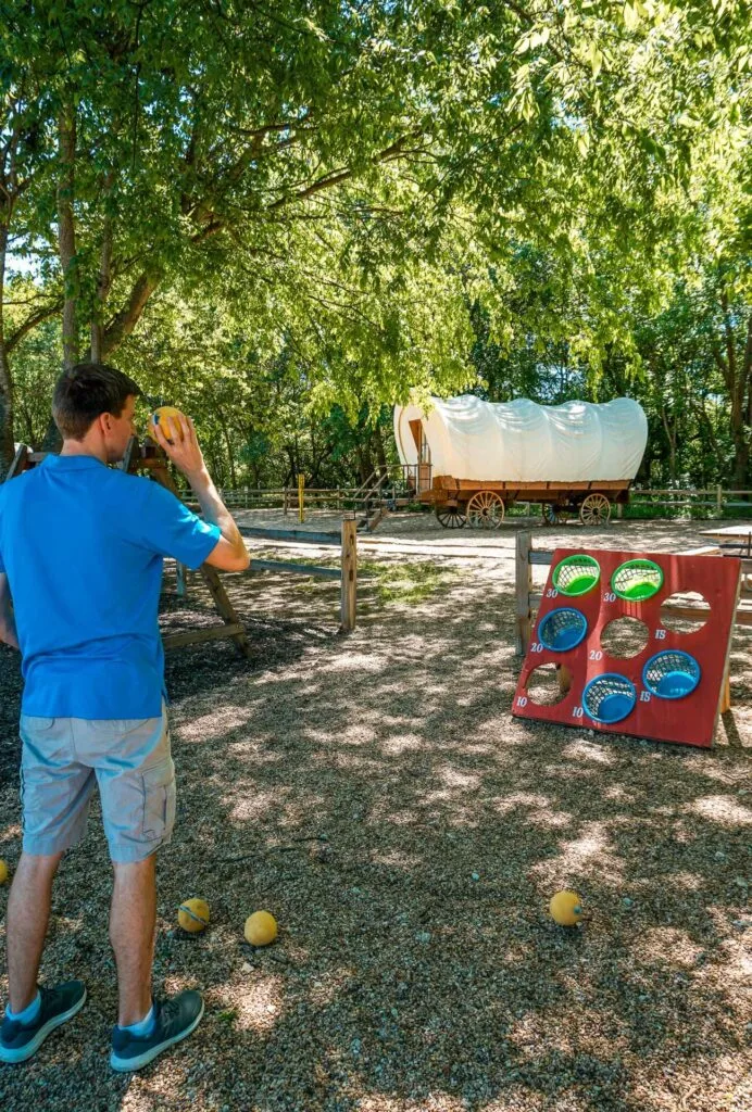 A man throwing a ball into buckets at The Silver Spur Resort's Wagon Junction. 