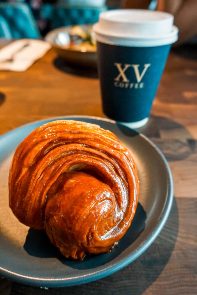 A fresh pastry with a coffee cup in the background from The Henry in Dallas.