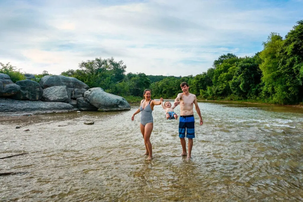 A couple swimming their son in the Paluxy River at Big Rocks Park - one of the best FREE things to do in Glen Rose, Texas.
