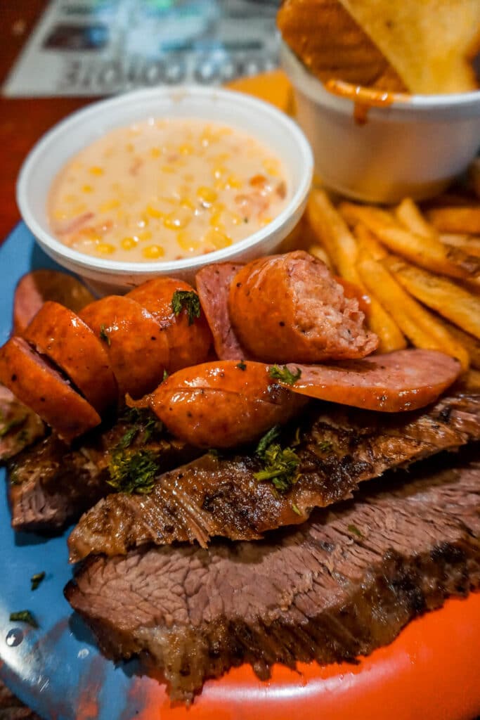 A plate of sausage, brisket, bowl of cream corn, fries, and Texas toast from Loco Coyote in Glen Rose, Texas.