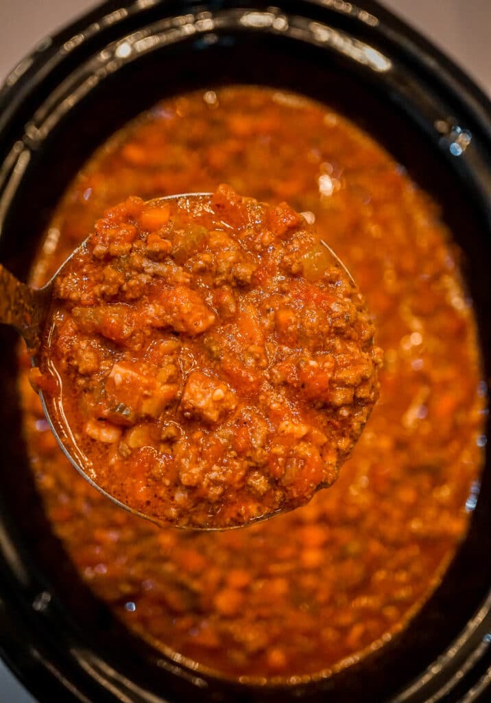A ladle of Bolognese Sauce of a slow cooker filled with more of the Ragù.