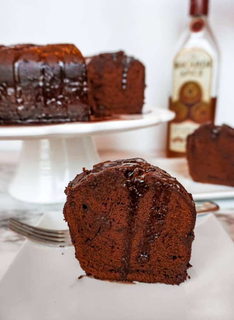A slice of Chocolate Rum Cake with a chocolate rum syrup drooping down the sides.
