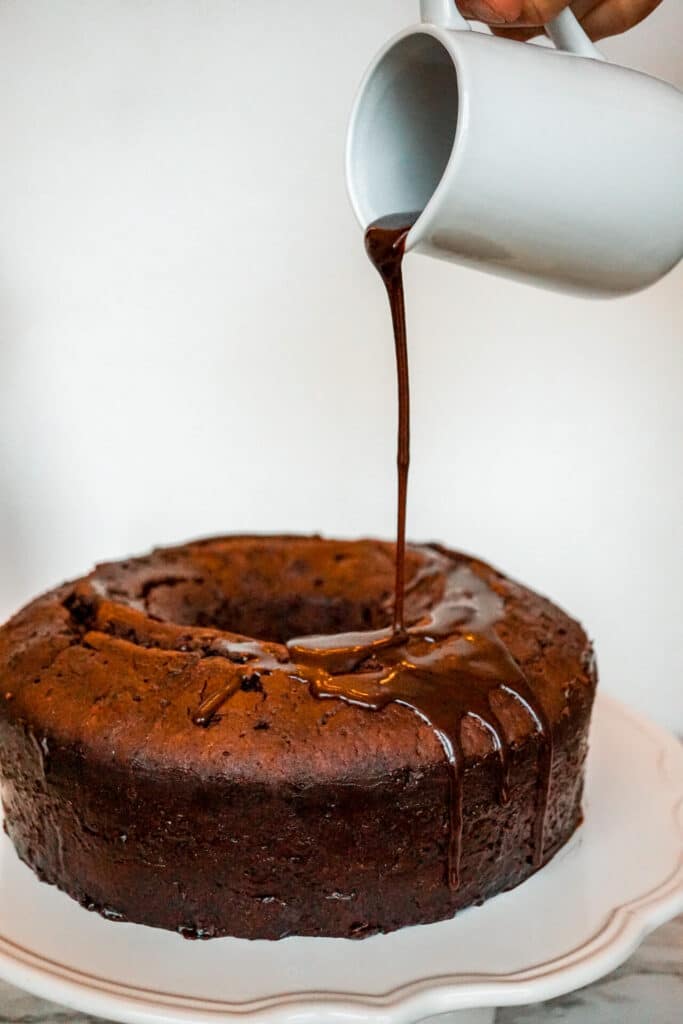 Someone pouring a chocolate rum syrup over a Chocolate Rum Cake.