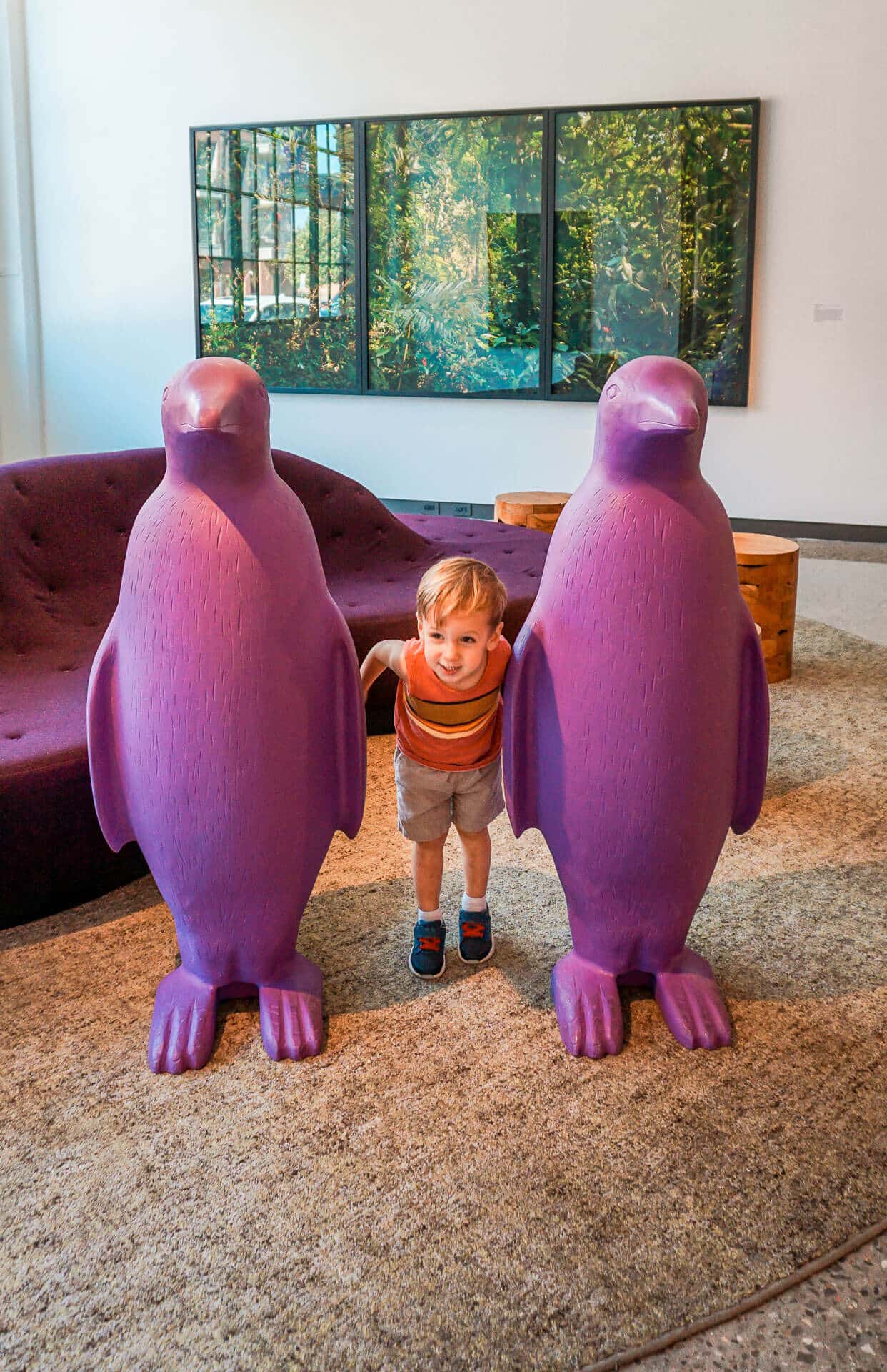 A toddler boy between two purple penguin statues at 21c Museum Hotel in Oklahoma City.