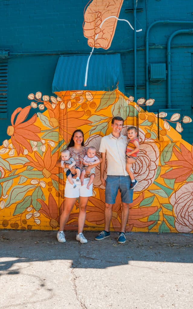 A family of five in front of a beautiful floral mural at Plaza Walls.