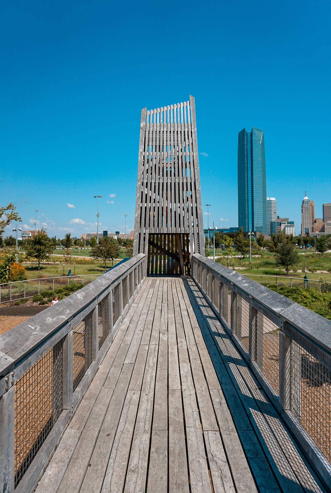 A wooden bridge to the tower with slides at Scissortail Park - playing here is one of the best things to do in Oklahoma City with toddlers.