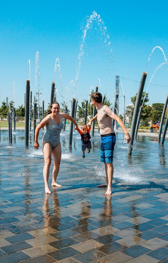 A mother and father shining their son at a splash pad at Scissortail Park in Oklahoma City.