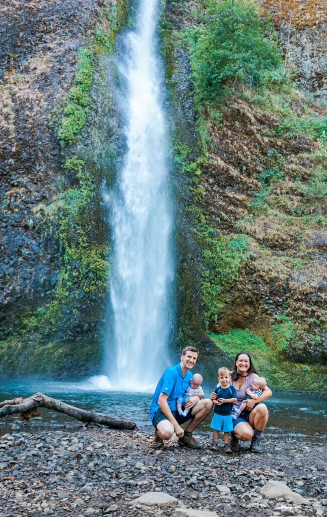 Family of five on a bed of rocks in front of one of the best waterfalls in Columbia River Gorge - Horsetail Falls.